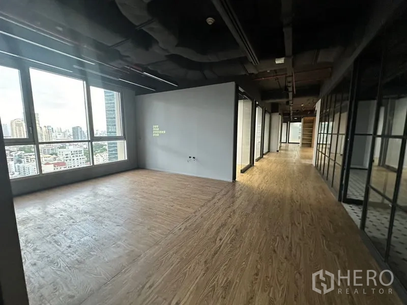 Office Space for rent in Bang Rak, Bangkok - Corner workspace by large windows next to a hallway with glass partitions.