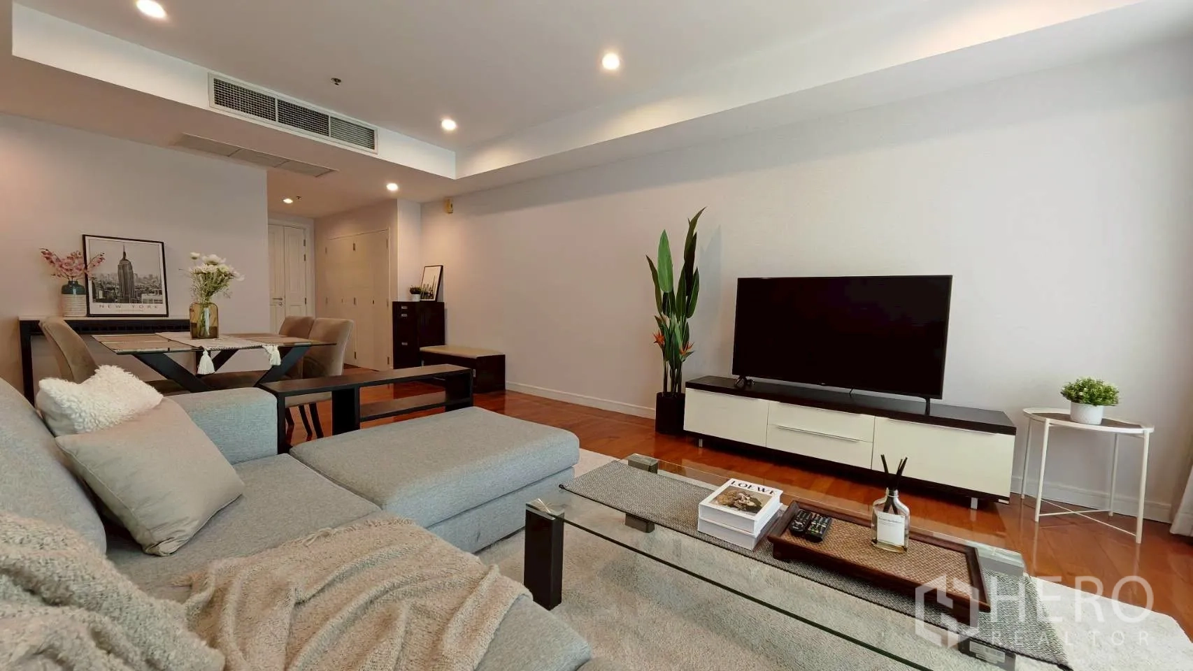 Condominium for rent in Khlong Toei, Bangkok - Living room with TV console, glass coffee table and sectional sofa.