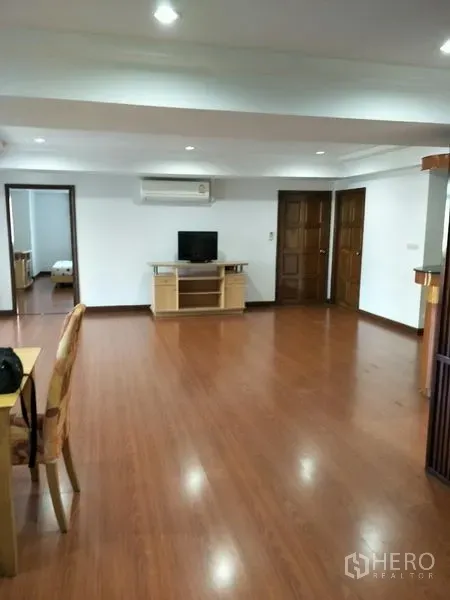 Condominium for rent in Watthana, Bangkok - Wide living area with TV console, air-conditioning, and doorways leading to bedrooms.