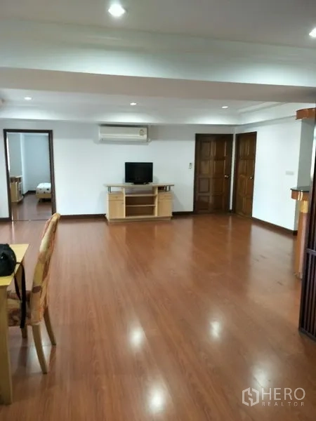Condominium for rent in Watthana, Bangkok - Wide living area with TV console, air-conditioning, and doorways leading to bedrooms.