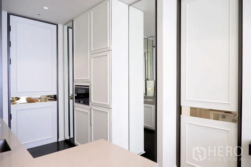 公寓 出租在Pathum Wan, Bangkok - 高挑白色厨房柜体，内置烤箱与镜面板