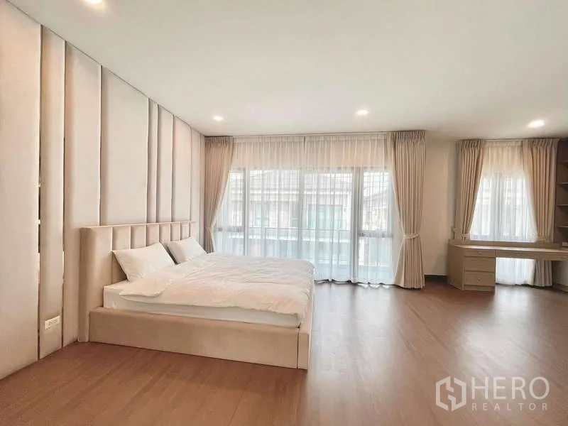 Detached House for rent in Bang Phli, Samut Prakan - Spacious master bedroom with wood flooring, padded feature wall and sheer curtains opening to a balcony.