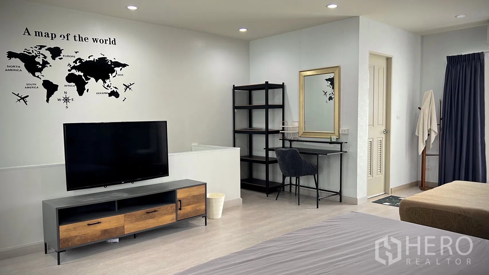 Townhouse for rent in Bang Kapi, Bangkok - Bedroom corner with TV console, shelving unit and vanity next to a wall map decal.