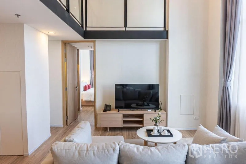 คอนโด ให้เช่าในKhlong Toei, Bangkok - ห้องนั่งเล่นเพดานสูง พร้อมชั้นวางทีวี โต๊ะกาแฟ และประตูสู่ห้องนอน