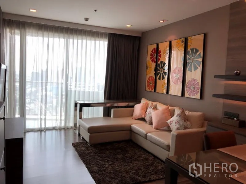 คอนโด ให้เช่าหรือขายในWatthana, Bangkok - ห้องนั่งเล่นพร้อมโซฟา L เปิดสู่ระเบียงผ่านผ้าม่านโปร่ง มองเห็นวิวเมือง