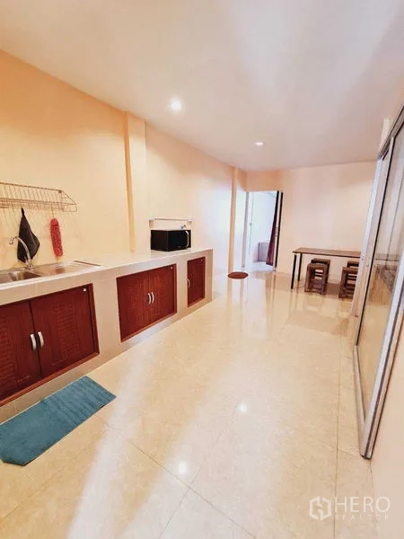 Shophouse for sale in Lam Luk Ka, Pathum Thani - Long kitchen with sink, built-in wooden cabinets and sliding glass door.