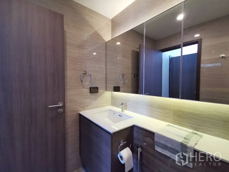 公寓 出售在Phra Khanong, Bangkok - 现代公寓浴室，超大镜柜、木质洗手台与背光镜面，风格简洁。