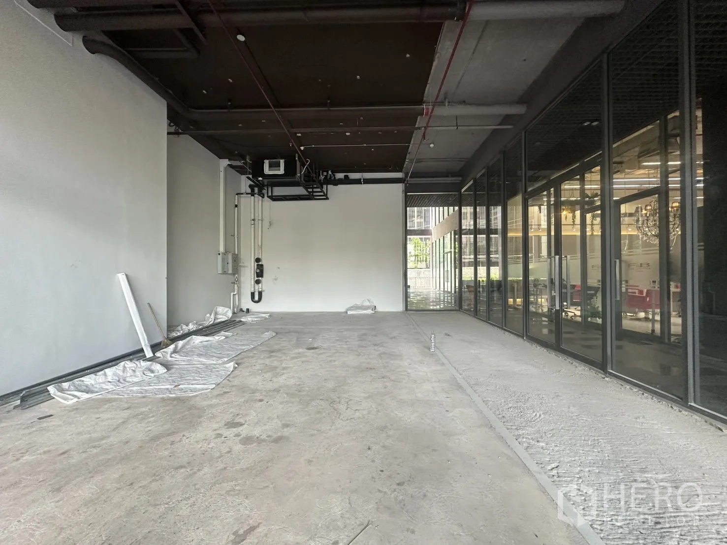 Retail Space for rent in Khlong Toei, Bangkok - High exposed ceiling with ductwork and side glass partition bringing natural light.