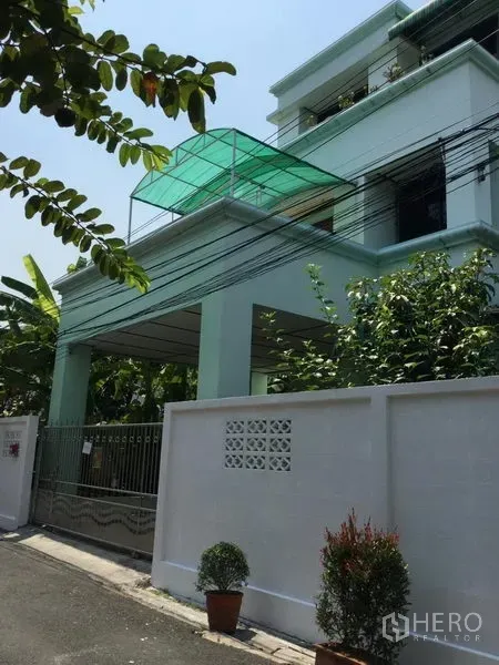 独立式住宅 出租或出售在Huai Khwang, Bangkok - 外观为薄荷绿色多层独栋住宅，带有院门车位与屋顶篷棚。