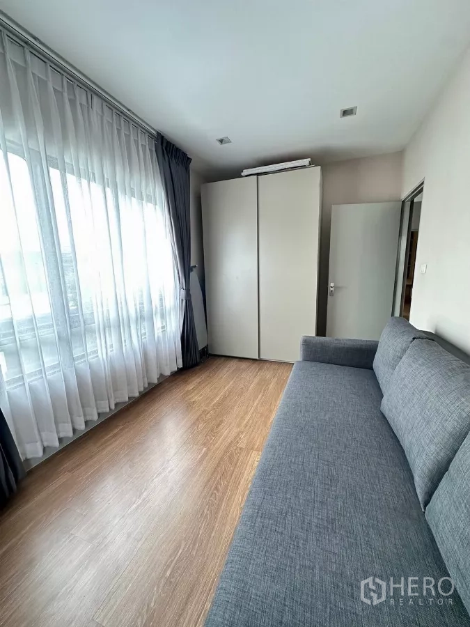 Detached House for rent in Saphan Sung, Bangkok - Secondary bedroom with large grey sofa bed and wardrobe.