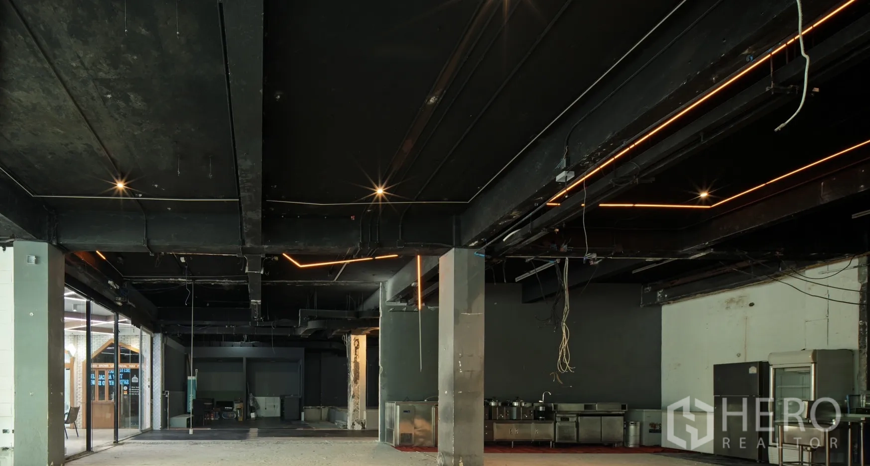 零售空间 出租在Watthana, Bangkok - 开阔平面，工业风天花、线性灯带及不锈钢备餐设备。