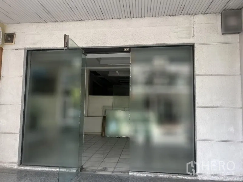 零售空间 出租在Watthana, Bangkok - 宽幅玻璃入户门，通向铺内瓷砖空间。