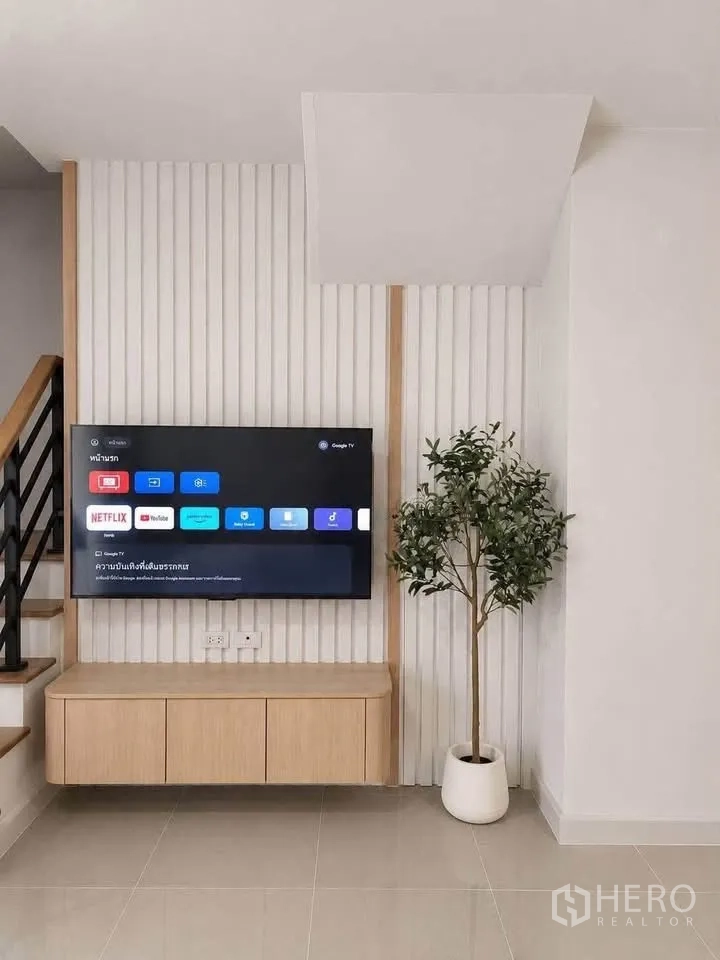 联排别墅 for rent in Bang Phli, Samut Prakan - 电视特色墙搭配悬空柜与楼梯旁的绿植。