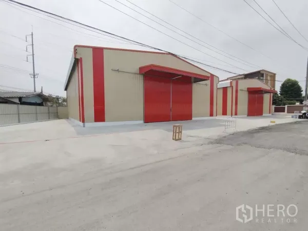 Warehouse for rent in Sai Mai, Bangkok - Front exterior of new warehouse buildings with red sliding doors and a wide concrete yard in Sai Mai, Bangkok.