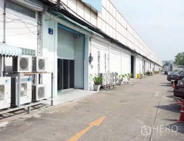 Warehouse for rent in Bang Na, Bangkok - Warehouse exterior in Bang Na with roll-up loading door, AC units and a wide truck-access driveway.