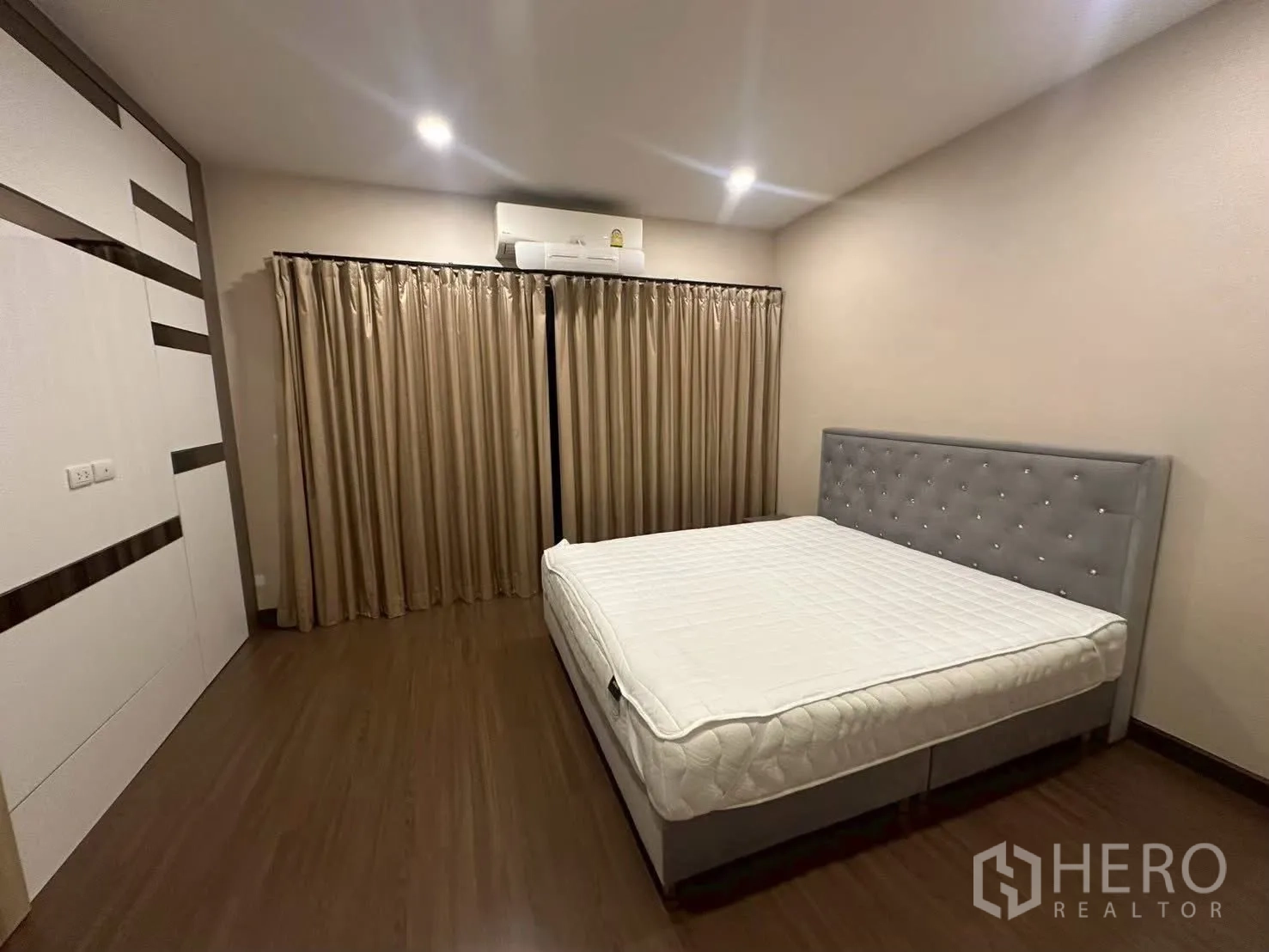 独栋房屋 for rent in Bang Phli, Samut Prakan - 大卧室设灰色床头板、整面窗帘与壁挂空调。