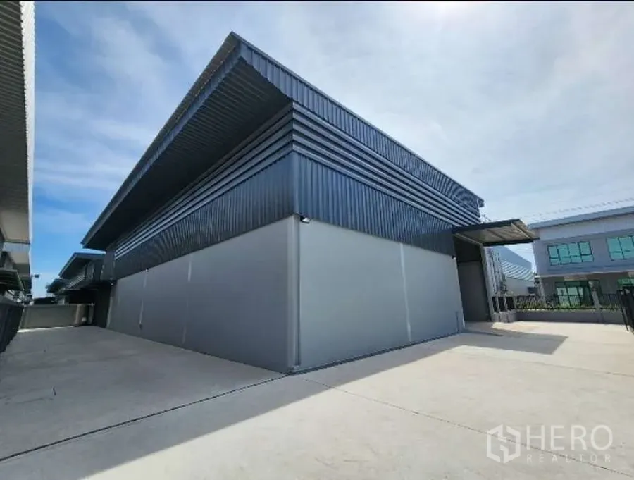 Factory for rent in Bang Bo, Samut Prakan - Street-facing view of steel-clad factory building with a wide driveway