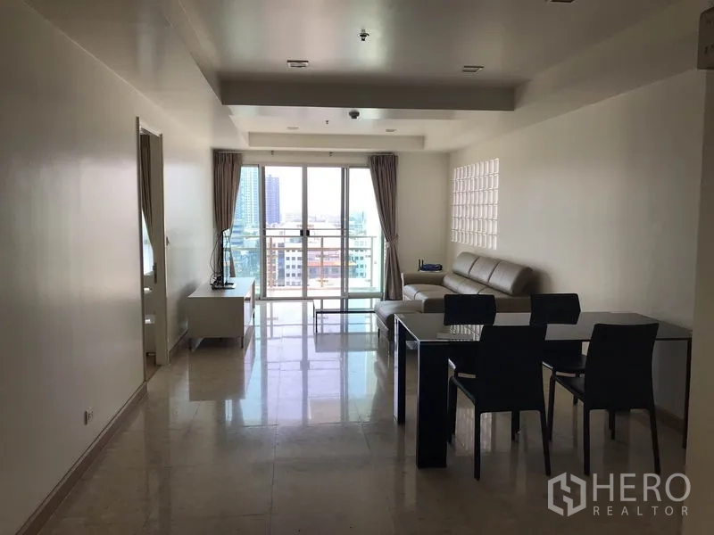 Condominium for rent in Khlong Toei, Bangkok - Living and dining area leading to a balcony with floor-to-ceiling sliding doors.
