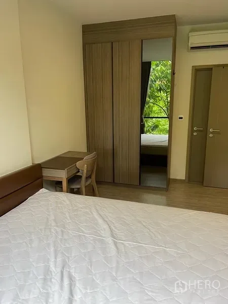 Condominium for rent in Watthana, Bangkok - Bedroom with built-in wardrobe, desk and air conditioner.