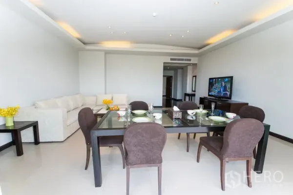 Condominium for rent in Sathon, Bangkok - Dining area set for six beside a spacious lounge with recessed ceiling lights.