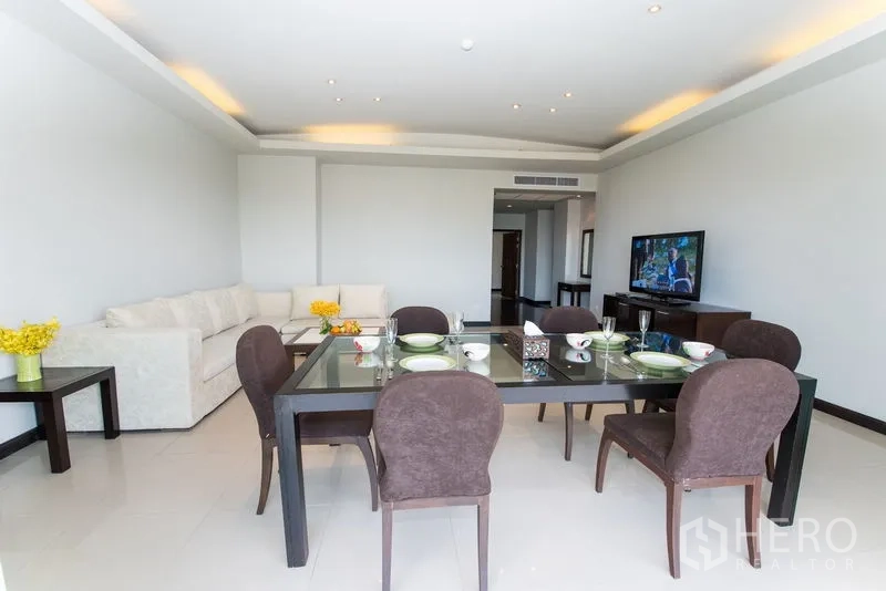 Condominium for rent in Sathon, Bangkok - Dining area set for six beside a spacious lounge with recessed ceiling lights.