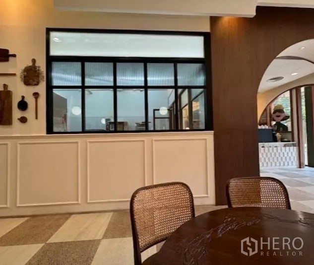 零售空间 出租在Watthana, Bangkok - 咖啡馆风格内饰，米色墙板、黑框窗与藤椅。