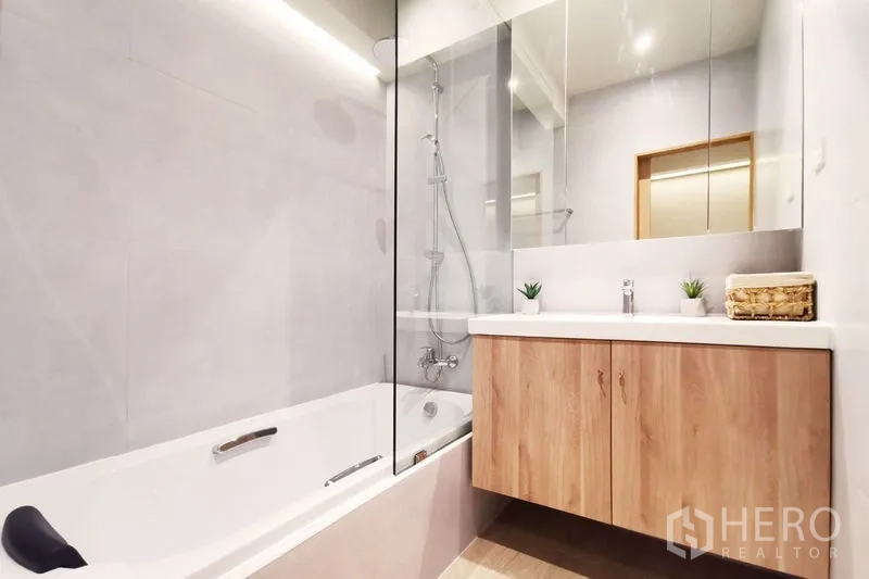 联排别墅 出租在Khlong Toei, Bangkok - 现代卫浴，浴缸带玻璃隔断与木质洗手台、镜柜。