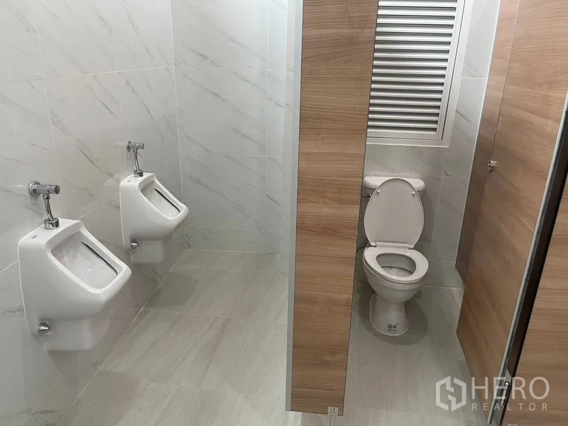 Home Office for rent or sale in Wang Thonglang, Bangkok - Restroom with toilet cubicle and twin urinals in office building.