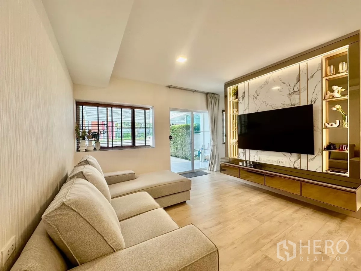 联排别墅 出租在Prawet, Bangkok - 客厅，大理石电视背景墙与沙发，木地板铺设。