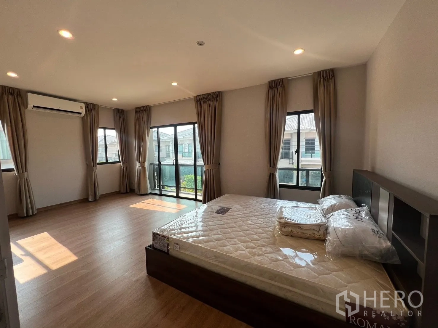 Detached House for rent in Bang Phli, Samut Prakan - Spacious master bedroom with balcony access, several windows and an air-conditioning unit.