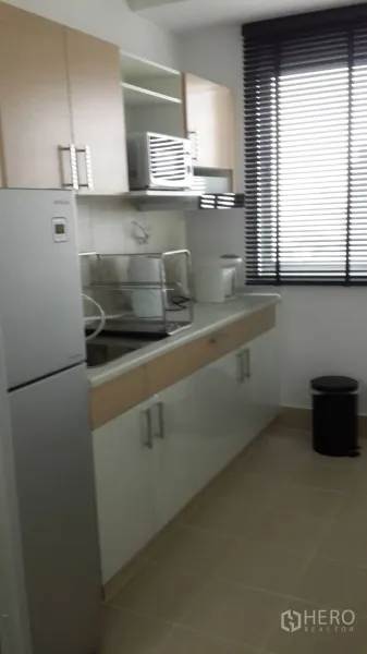 Condominium for rent in Huai Khwang, Bangkok - Bright separate kitchen with cabinets, countertop, sink and large fridge at Supalai Park Ekkamai-Thonglor condo in Huai Khwang.