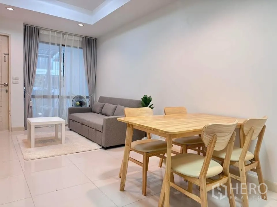 联排别墅 for rent in Phra Khanong, Bangkok - 餐区设木质餐桌椅，旁为灰色沙发。