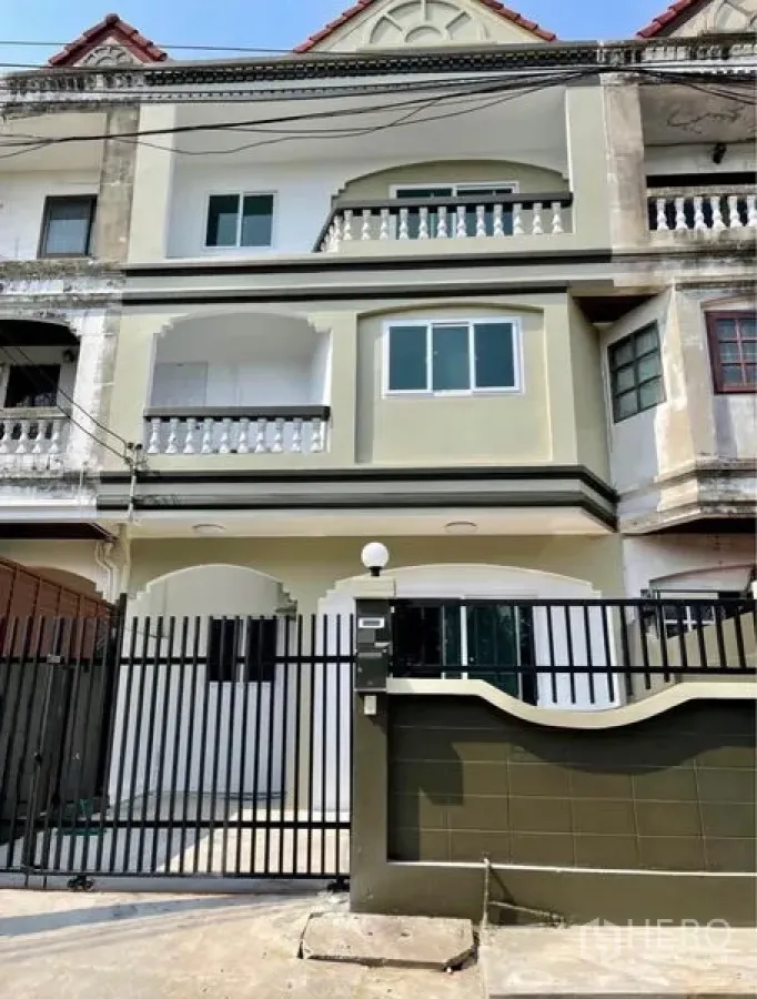 Townhouse for rent - Three-storey gated townhouse exterior with balconies and updated windows.