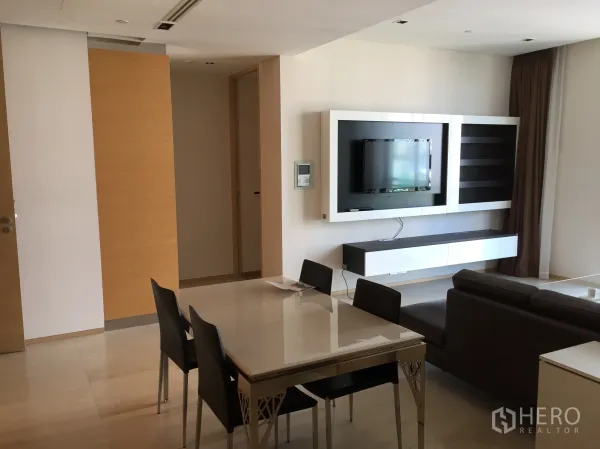 公寓 出租或出售在Bang Rak, Bangkok - 现代公寓中的电视背景墙与悬空柜，对面为用餐区。