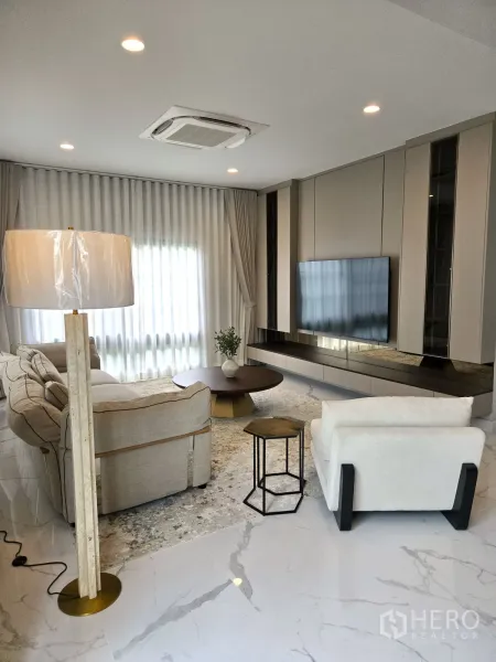 Detached House for rent in Bang Phli, Samut Prakan - Ground-floor living area with large sofa set, TV wall and full-height curtains.