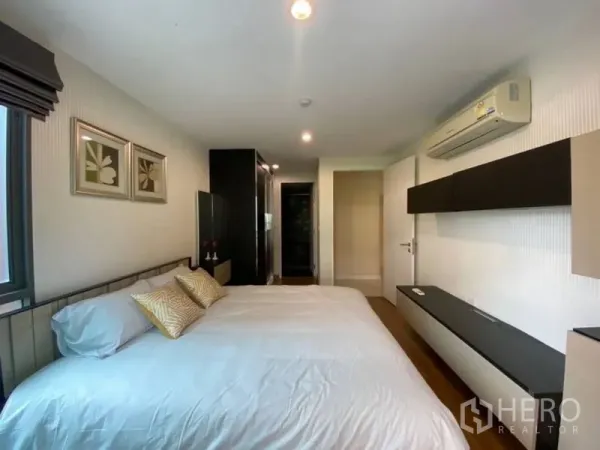 Condominium for rent in Watthana, Bangkok - Bright bedroom with king bed, wall-mounted shelves, framed art and split air conditioner.