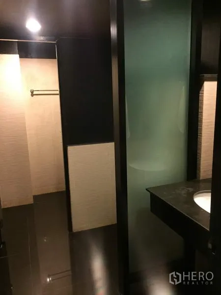 零售空间 出租在Khlong Toei, Bangkok - 现代化卫生间，磨砂玻璃隔断与石质洗手台，深色地砖。