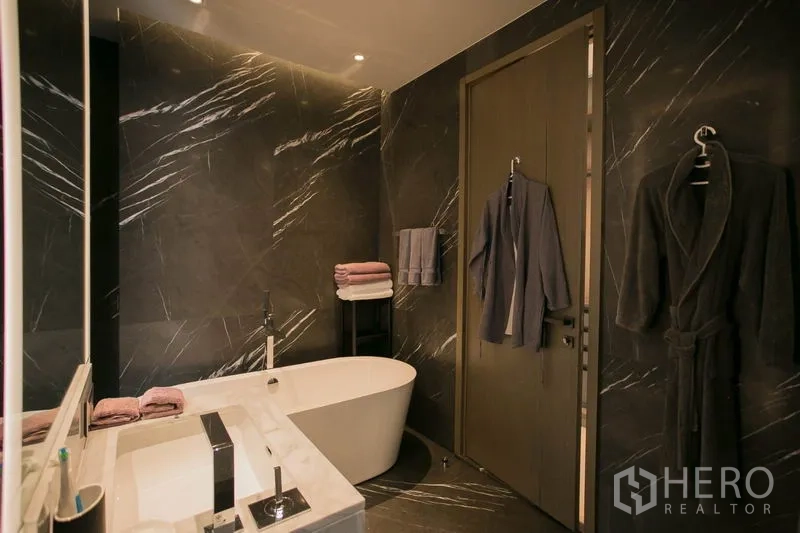 Condominium for rent or sale in Watthana, Bangkok - Luxurious bathroom featuring freestanding bathtub, dark marble tiles and vanity.