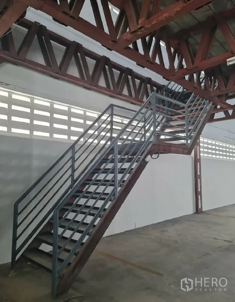 Warehouse for rent in Khlong Toei, Bangkok - Metal staircase leading to the mezzanine level along a steel truss wall.