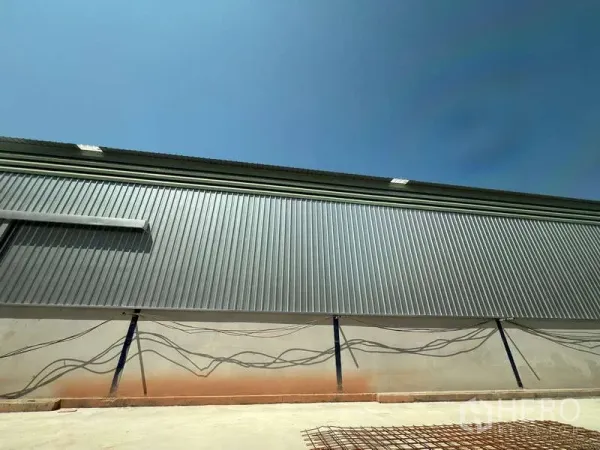 Warehouse for rent in Lat Krabang, Bangkok - Corrugated metal exterior of a modern warehouse with paved loading apron under a clear sky in Lat Krabang, Bangkok.