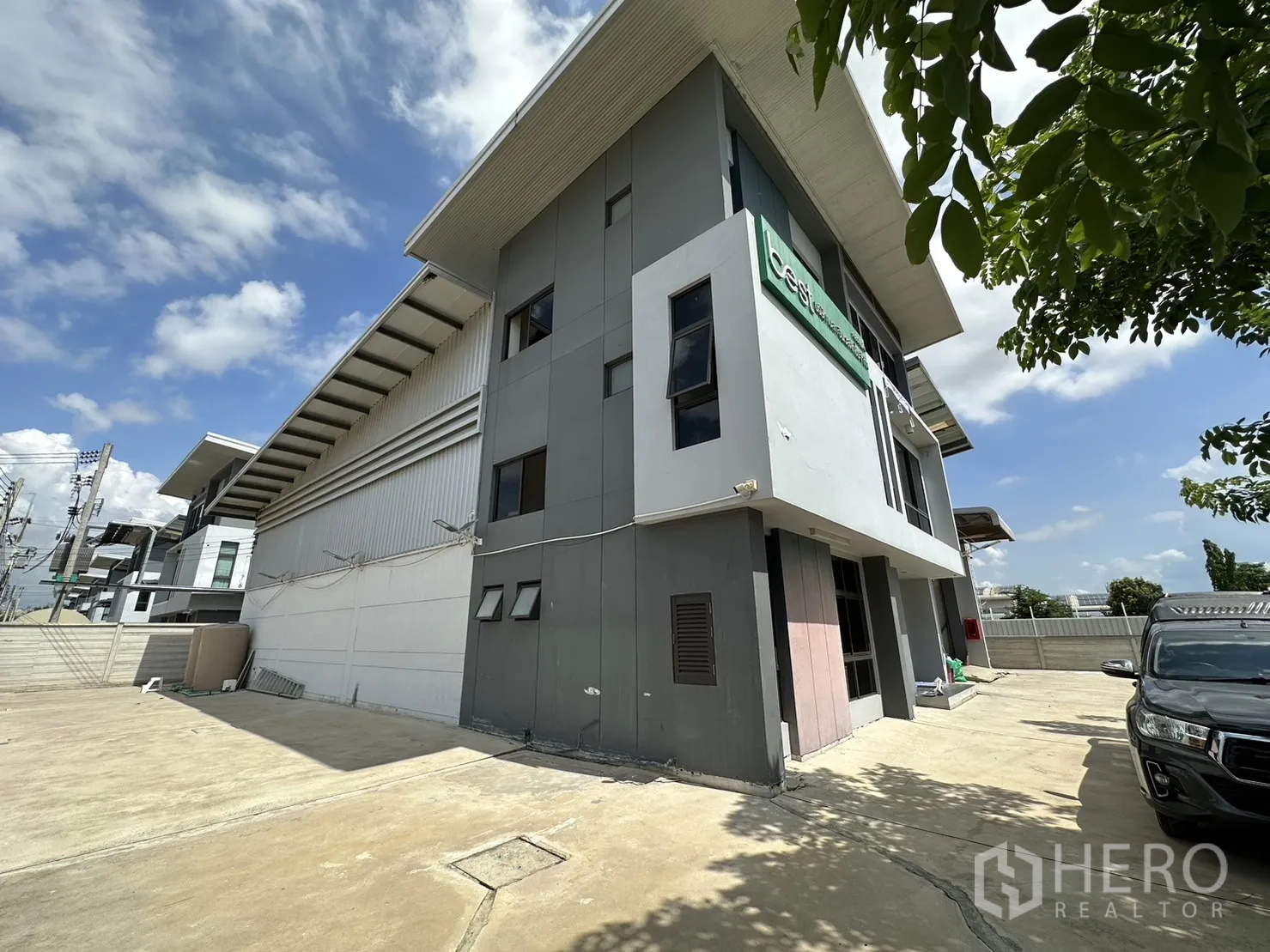 工厂 出租或出售在Pathum Thani - 转角外立面，可见办公楼与高顶厂房相连。