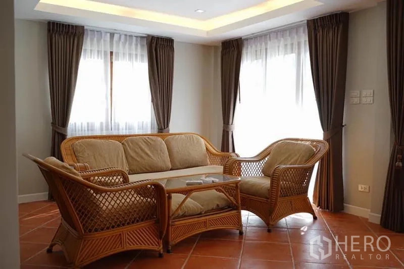 Detached House for rent in Wang Thonglang, Bangkok - Bright living room with rattan sofa set, coffee table and large curtained windows.
