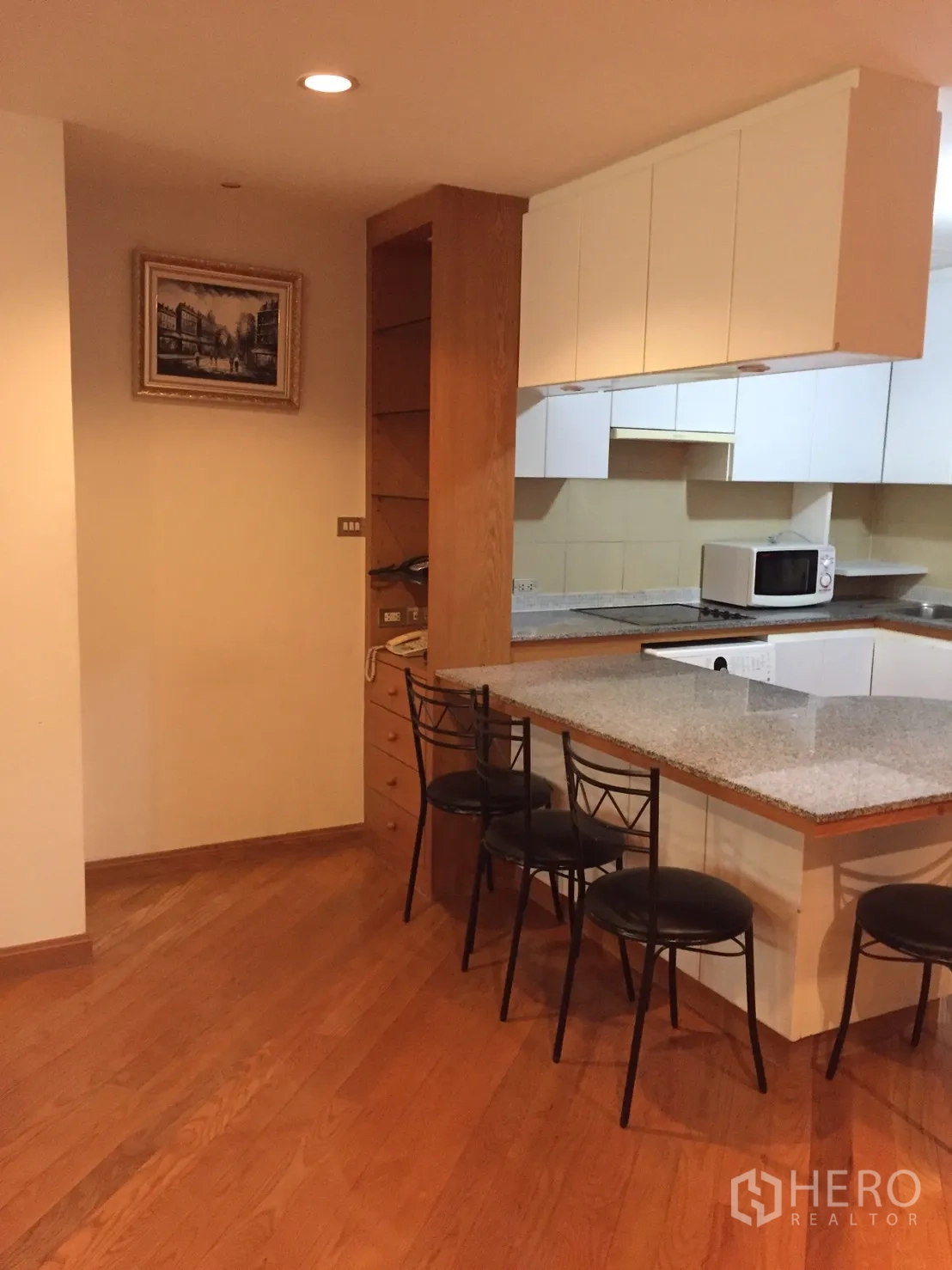 คอนโด ให้เช่าในPathum Wan, Bangkok - ครัวแบบเปิดพร้อมเคาน์เตอร์หินแกรนิต ตู้ลอยสีขาว ไมโครเวฟ และสตูลบาร์สีดำ 4 ตัว