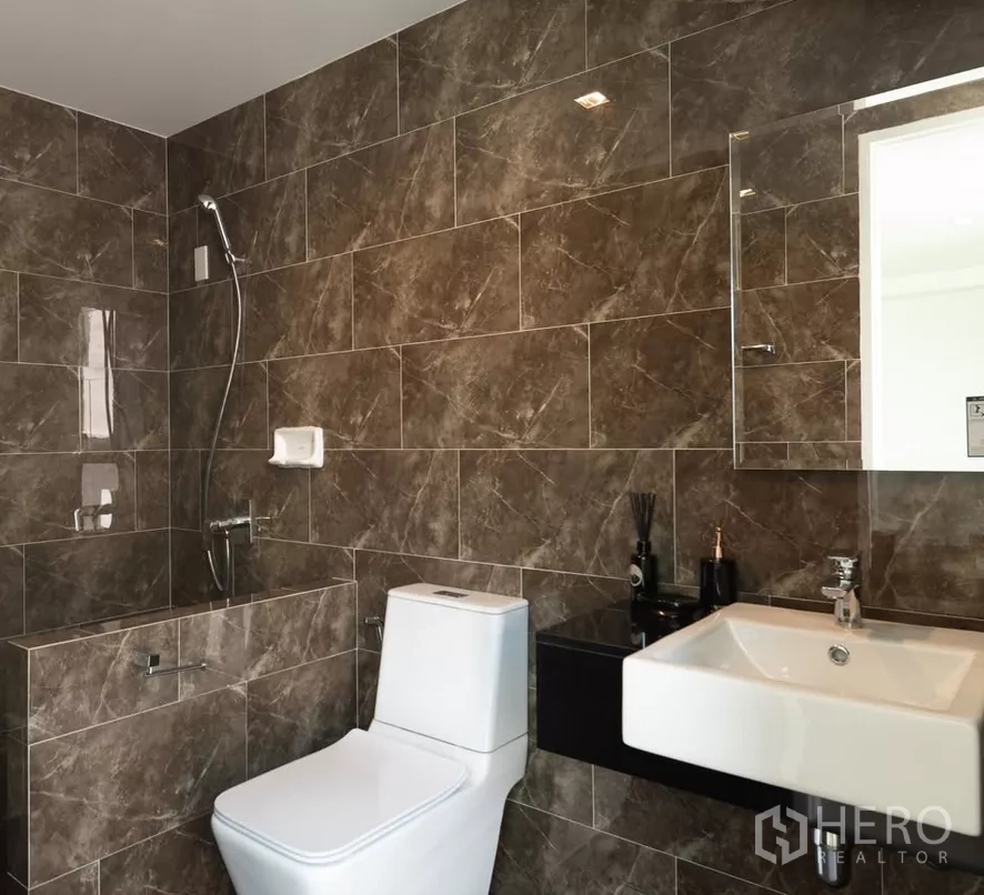 Home Office for sale in Bang Kapi, Bangkok - Contemporary bathroom with brown marble tiles, walk-in shower, and white sanitaryware.