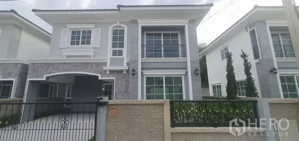 独立式住宅 出租在Nonthaburi - 带大门的现代两层住宅，设阳台与车道，位于暖武里巴革区社区内。