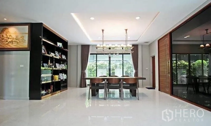 บ้าน ให้เช่าในBang Khae, Bangkok - ห้องรับประทานอาหารโปร่งสว่าง มีโคมแชนเดอเลียร์และประตูหน้าต่างบานใหญ่รับวิวสวน