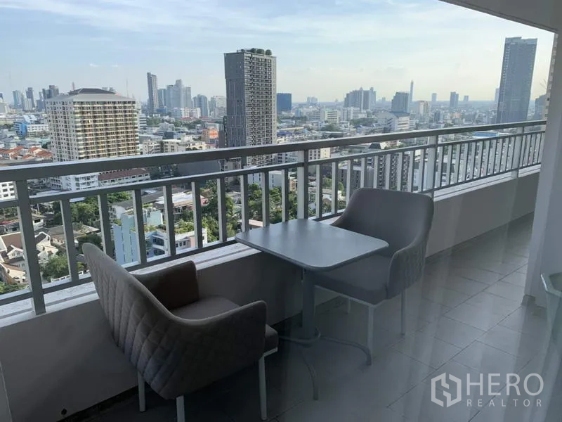 Condominium for rent in Sathon, Bangkok - High-floor balcony with seating and panoramic Bangkok skyline view.