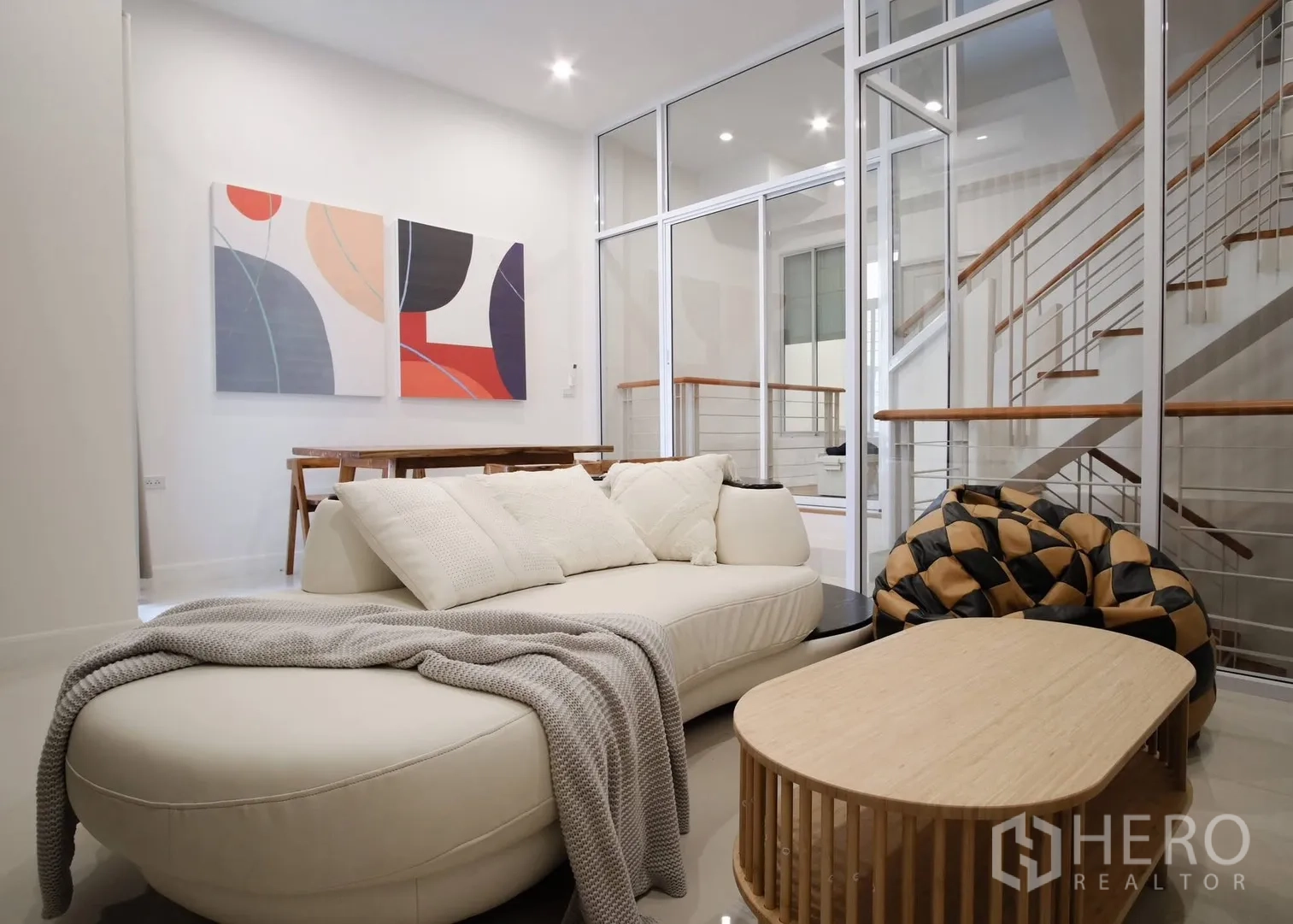 Townhouse for rent in Bang Phli, Samut Prakan - Contemporary living area with curved sofa, glass partition, and staircase.