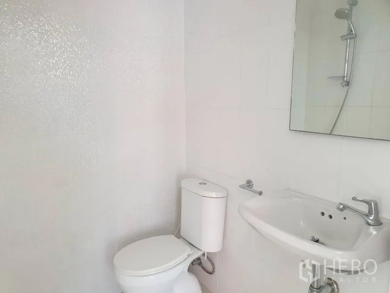 Detached House for rent in Khlong Toei, Bangkok - Clean white bathroom with toilet, sink and mirror.