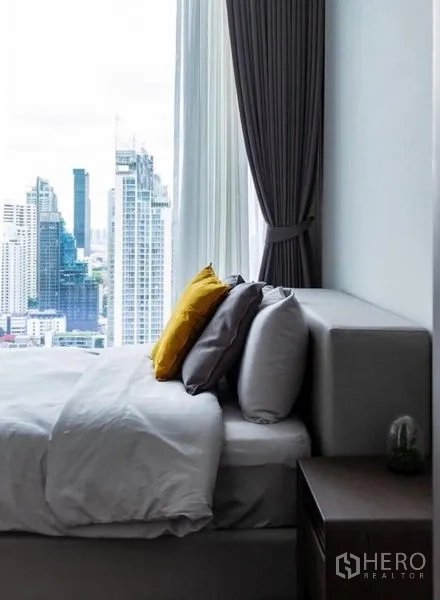 คอนโด ให้เช่า - เตียงติดหน้าต่างสูง มองเห็นวิวเมืองกว้างและผ้าม่านทึบ